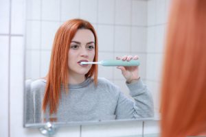 אישה מצחצחת שיניים לפני ביקור אצל רופא שיניים
